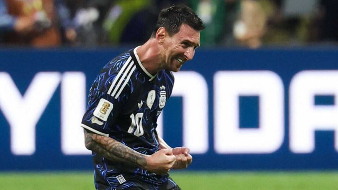Argentina number 10 celebrates on his knees during a 2026 World Cup match, fists clenched, wearing the dark blue Argentina kit